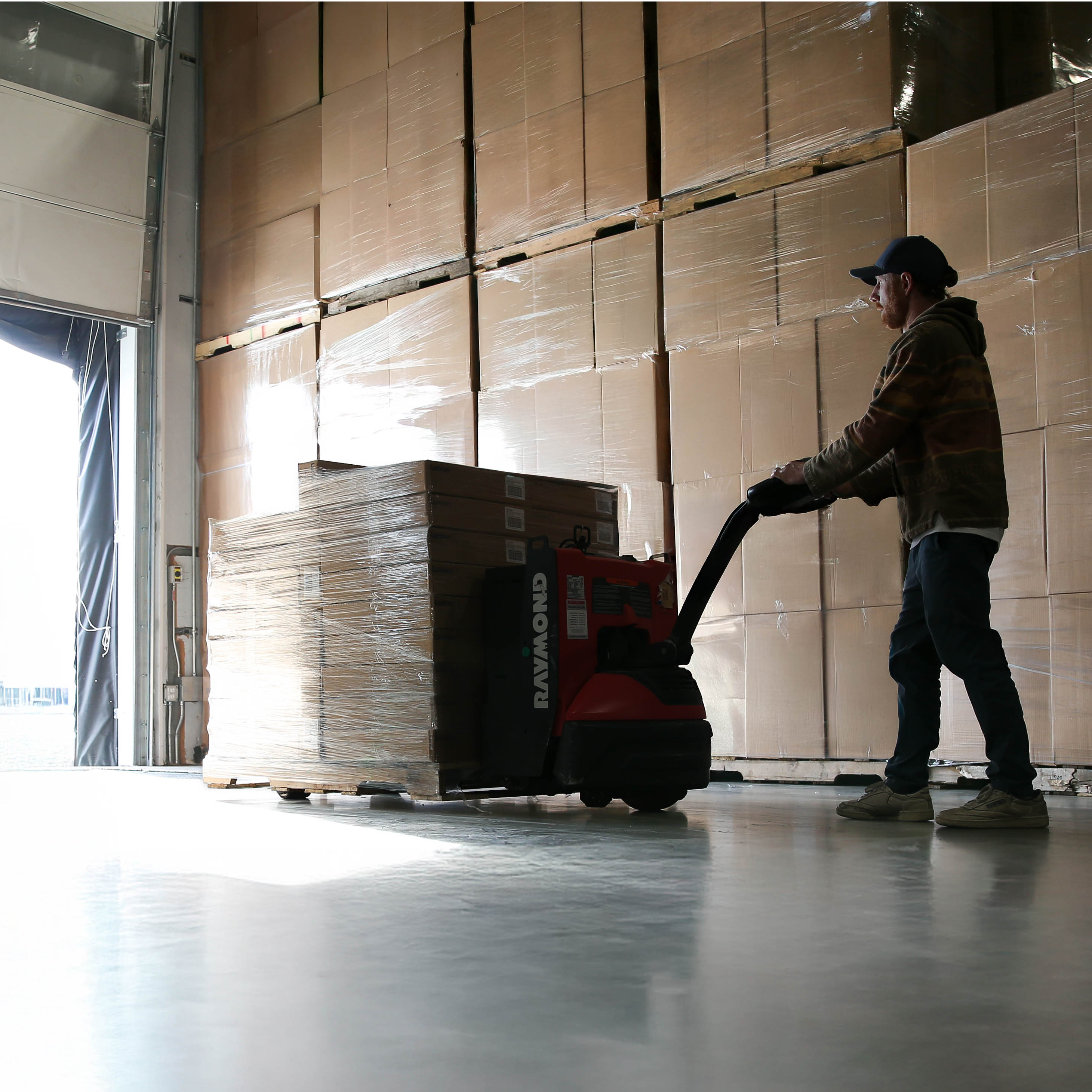 Pushing a pallet of boxes to a loading dock in a warehouse.